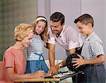 1960s HAPPY FAMILY IN BOWLING ALLEY LOOKING AT SCORE SHEETS BOY HOLDING BALL