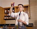 1960s MALE HIGH SCHOOL TEENAGE STUDENT IN CHEMISTRY LABORATORY HOLDING TEST TUBES