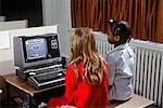 1980s TWO GIRLS LEARNING ABOUT COMPUTERS BY PLAYING ON SCREEN GAME