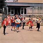 1960s GROUP OF SCHOOL CHILDREN RUNNING DOWN STEPS AWAY FROM SCHOOL BUILDING