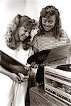 1980s 2 TEENAGE GIRLS READING VINYL RECORD ALBUM JACKET COVERS LISTENING TO LONG PLAYING PHONOGRAPH PLAYER