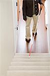 Blind woman using a walking stick on stairway