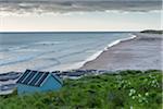 Fisherman's hut on the beach along the North Sea with dramatic cloudy sky at Bamburgh in Northumberland, England, United Kingdom