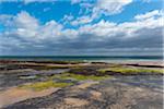 Rocky beach with dramatic clouds over the North Sea at Bamburgh in Northumberland, England, United Kingdom