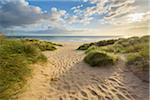 Footprints in the sand along a path on the beach at sunrise at the North Sea in Bamburgh in Northumberland, England, United Kingdom