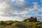 Scenic view of the grassy dunes and Bamburgh Castle in Bamburgh in Northumberland, England, United Kingdom