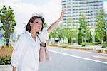 Young Japanese woman calling a taxi downtown Tokyo, Japan