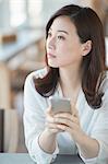 Japanese woman with smartphone in a stylish cafe