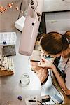 High angle view of female jeweller using hand tool at workbench