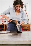 Female jeweller hammering bangle at workbench