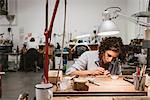 Female jeweller drawing at workbench