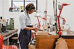 Female jeweller using blow torch at workbench