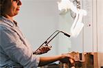 Female jeweller using flaming  blow torch at workbench