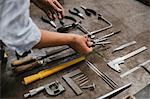 Hands of female jeweller laying out hand tools at workbench in jewellery workshop