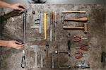 Overhead view of female jeweller's hands laying out hand tools at workbench