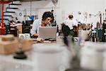 Female jeweller typing on laptop at workbench