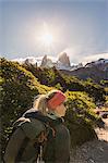 Female hiker hiking near sunlit  Fitz Roy mountain range in Los Glaciares National Park, Patagonia, Argentina