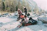 Adult bouldering friends taking off trainers at riverside, Lombardy, Italy