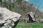 Adult bouldering friends climbing boulder, Lombardy, Italy