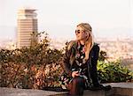 Blond haired female tourist sitting on wall, Barcelona, Spain