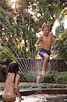 Young boy jumping into garden pool, mid-air