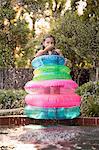 Young girl, standing in the middle of inflatable rings on the side of outdoor swimming pool