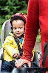 Woman walking with bicycle, young son sitting in child's seat of bike, mid section