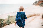 Mid adult woman walking towards beach, rear view