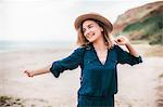 Mid adult woman dancing along beach, smiling