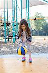 Girl bouncing basketball in playground