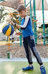 Boy bouncing basketball in playground