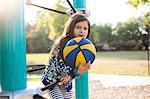 Girl holding basketball in playground