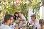 Family having lunch outdoor under grapevine trellis