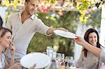 Man passing plate at outdoor family lunch