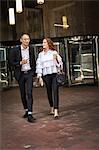 Young businesswoman and man with takeaway coffee strolling on sidewalk, New York, USA