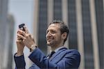 Smiling young businessman taking selfie outside office building, New York, USA