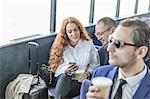 Young businesswoman and man looking at smartphone on passenger ferry