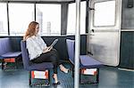 Stylish young businesswoman looking at digital tablet on passenger ferry