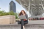 Young businesswoman sitting outside hotel using laptop, New York, USA