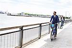 Young businessman cycling on waterfront, New York, USA