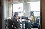 Two women working together in meeting room, brainstorming, using digital tablet