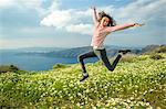 Girl jumping over flowers, O'a, Santorini, Kikladhes, Greece