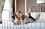 Woman using mobile phone on bed