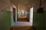 A view of a corridor in a derelict building full of sand. Vivid green coloured walls. Shadows