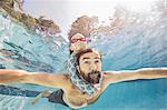 Underwater view of mature man swimming with daughter on piggy back