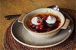 Close up of a dish of Creme Brulee with meringue and fresh red currants.