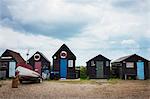 Row of traditional wooden fishing or fisherman's huts and a beached fishing boat on the sandy beach on the coast.