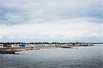 Long row of painted beach huts on a sandy beach overlooking the water.