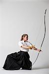 Caucasian woman practicing traditional Kyudo Japanese archery on white background