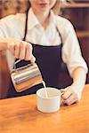 Close up of professional barista. Woman making coffee and pouring milk